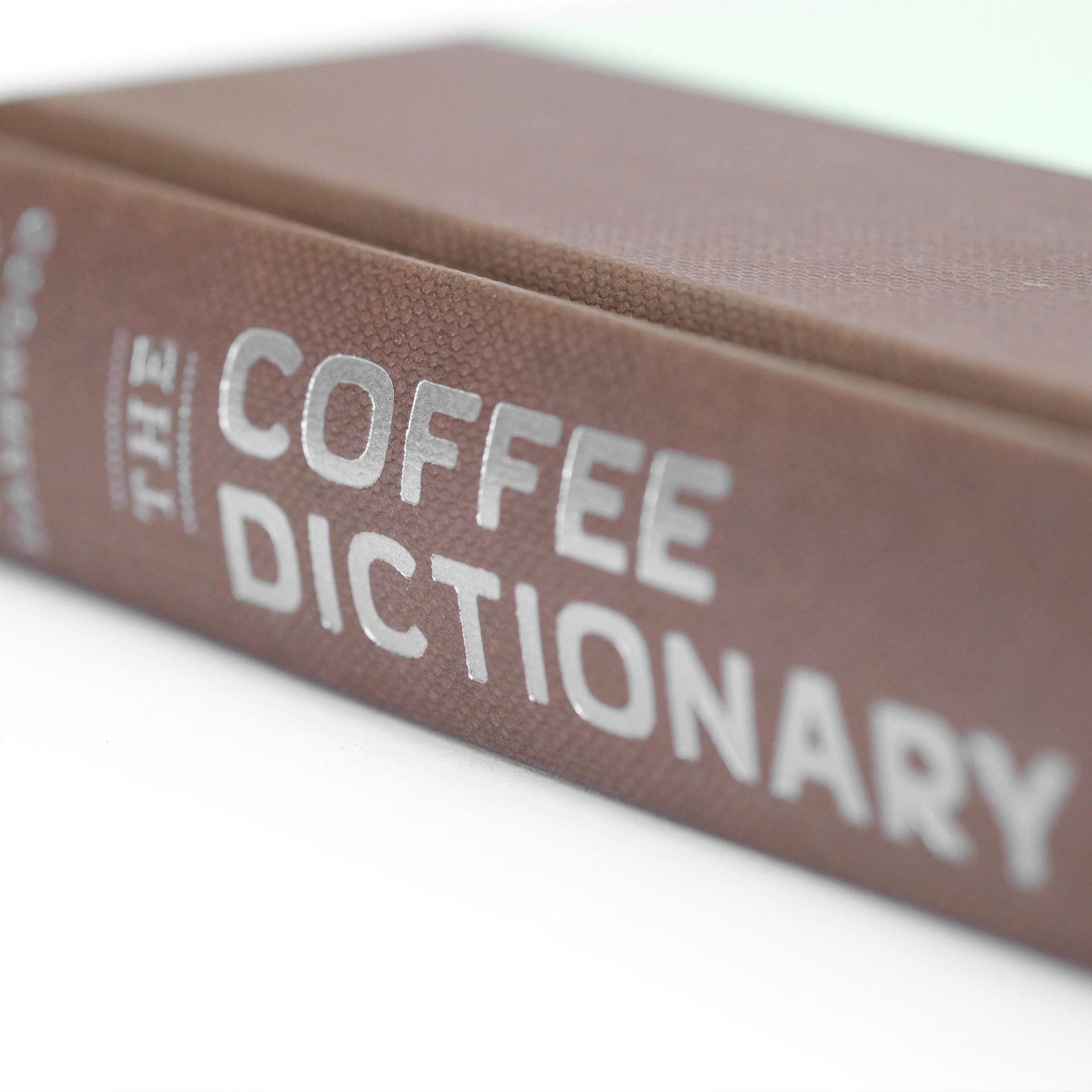 Close-up of "The Coffee Dictionary" accessory book by Cloud Picker Coffee, featuring detailed pages and coffee-related illustrations.