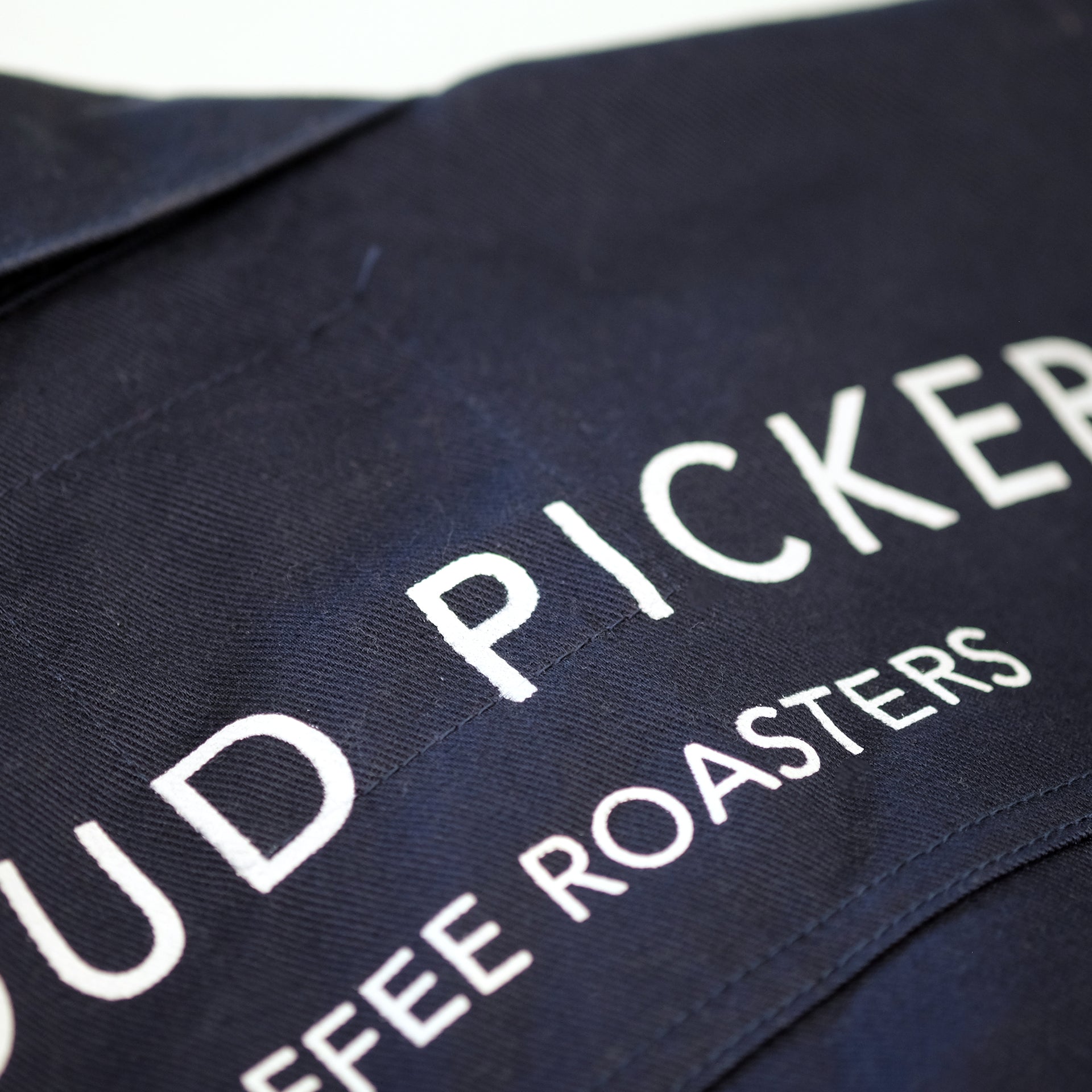 Unisex Cloud Picker Coffee roaster jacket made of durable fabric, featuring a sleek design with branding and adjustable collar.