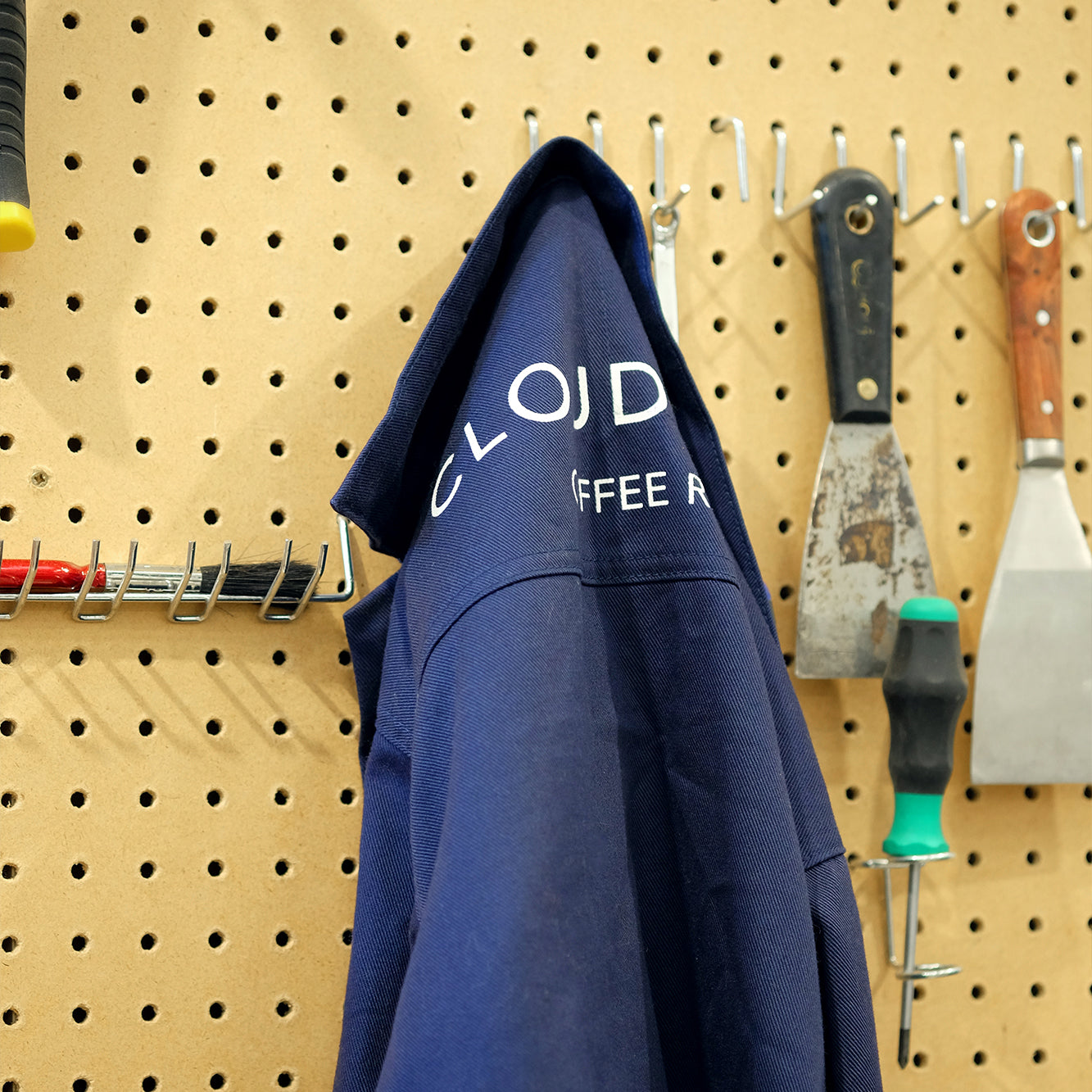Unisex Cloud Picker Coffee roaster jacket hanging on a display, made of durable fabric with branding details visible.