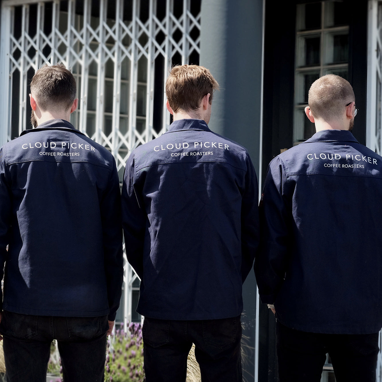 Unisex Cloud Picker Coffee roaster jacket hanging on a rack, showcasing durable merchandise for coffee roasting professionals.